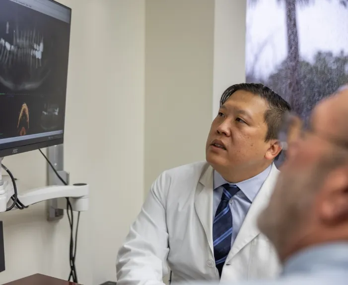 Doctor Koo showing a patient an x ray of their jaws and teeth