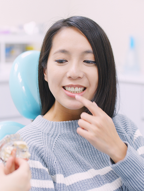 Woman pointing to her teeth while talking with her oral surgeon