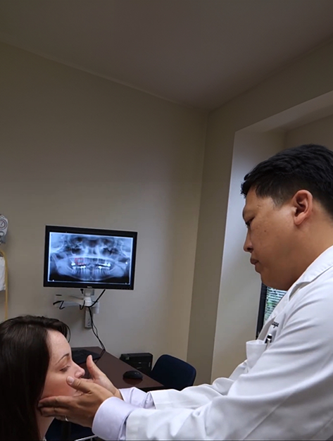 Houston oral surgeon examining a patient's face