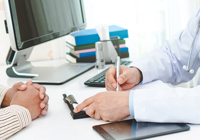 a front desk staff handing a patient forms to fill out