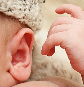 Close up of a baby's hand next to their ear