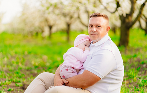 Man holding his baby while sitting in a park