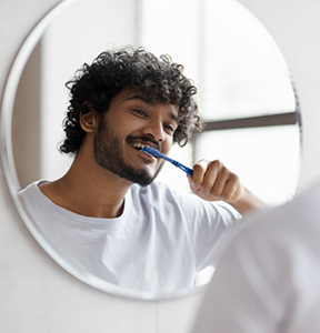Young man brushing his teeth at home