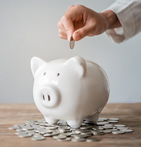 Person putting a coin into a piggy bank