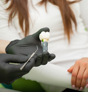 Oral surgeon showing a dental implant to a patient