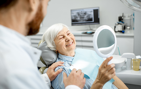 Senior dental patient admiring her smile in a mirror
