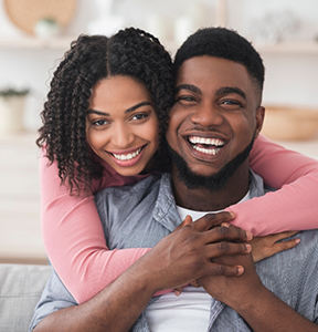 Young couple embracing and smiling at home