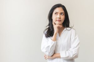 Young woman in white blouse, wearing thoughtful expression