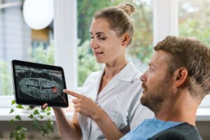 Dental team member and patient looking at X-ray of wisdom tooth