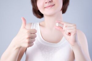 Woman holding her extracted tooth, making thumbs up